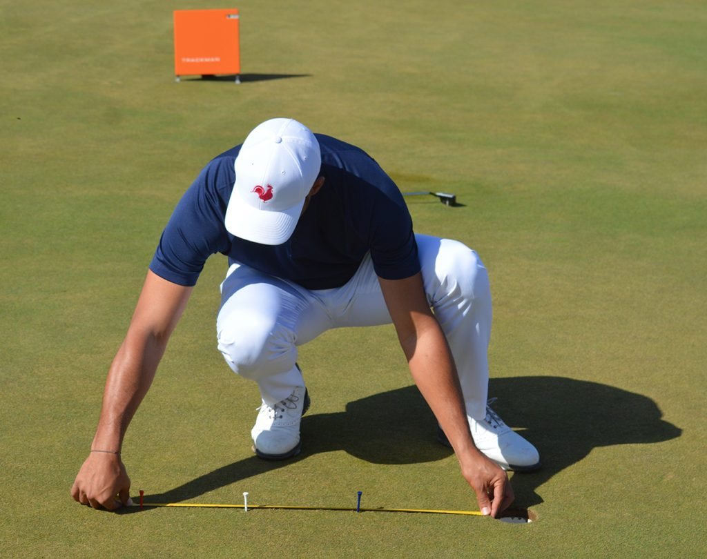 Alvin Pivaty mesurant une distance au mètre ruban sur un green d'entraînement à Marrakech